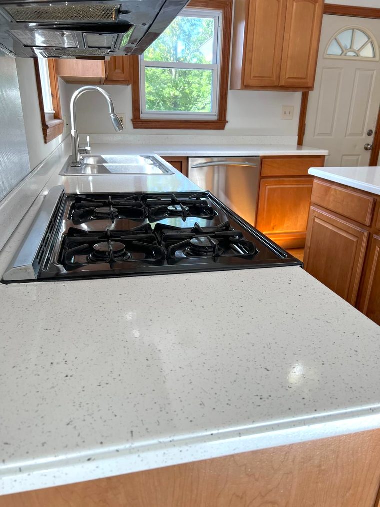 The same kitchen countertop after resurfacing, in a white speckled finish