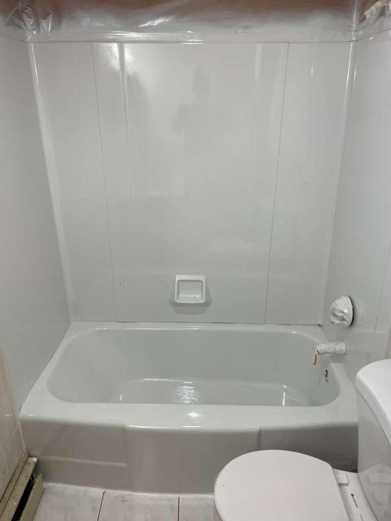 The same fiberglass tub and wall surround after refinishing, in bright white